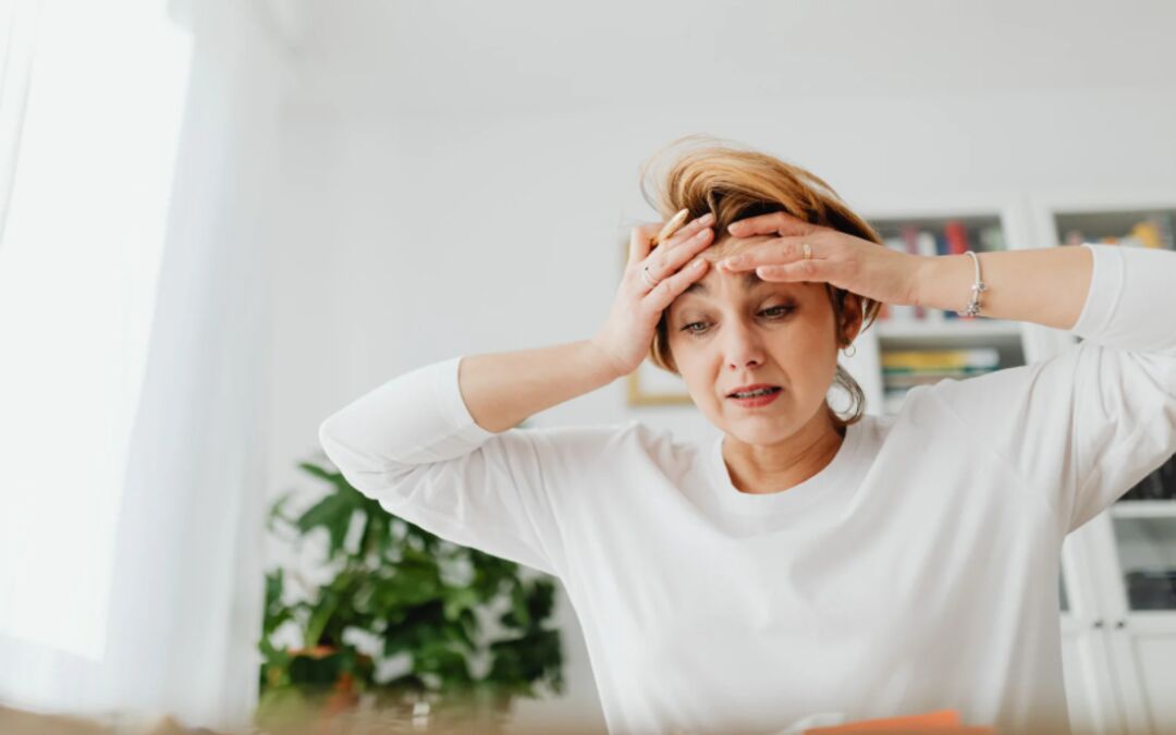Donna di mezza età con espressione di stress e confusione mentale si tocca la fronte, sintomi ADHD in menopausa